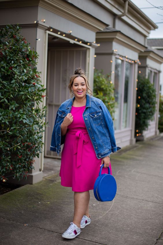 Look plus size vestido rosa, jaqueta jeans e bolsa azul clássico.