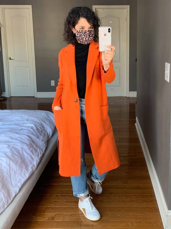 look calça jeans e casaco laranja e mascara protetora